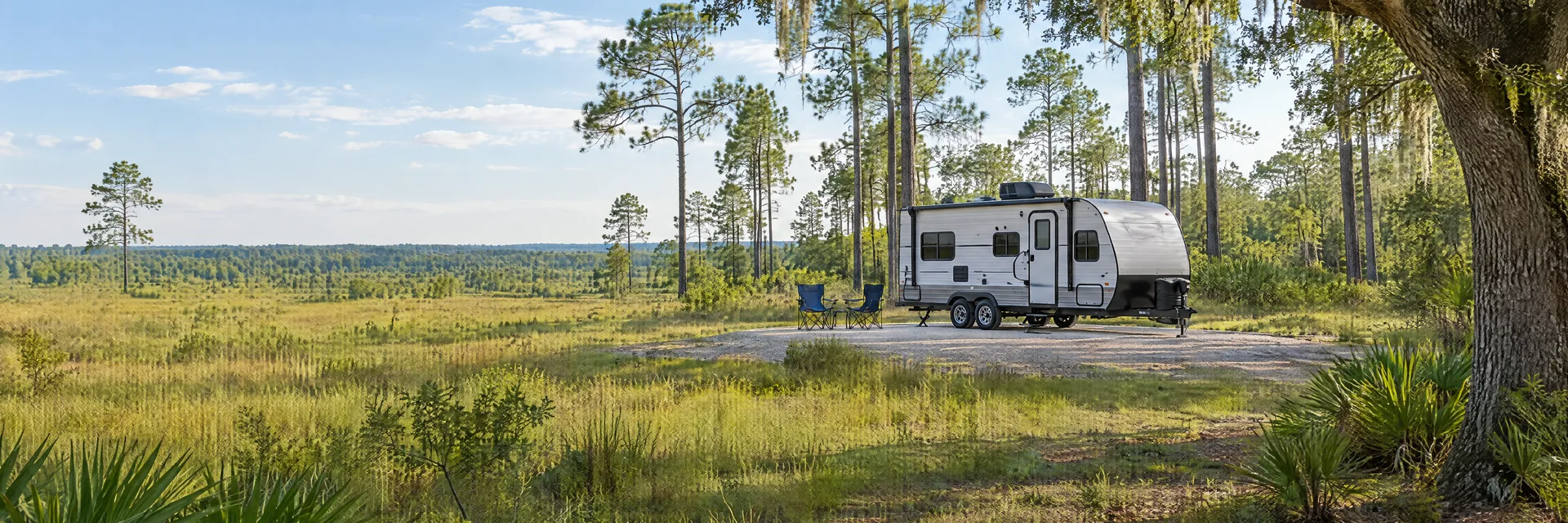 Illustration of a compact travel trailer at a fictional camping setting inspired by Summerdale, AL.