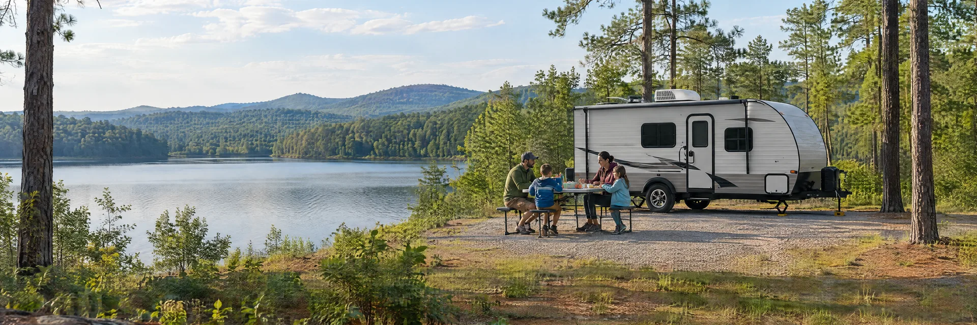 Illustration of campers enjoying a family picnic beside a compact travel trailer in a fictional camping setting inspired by Talladega, AL.