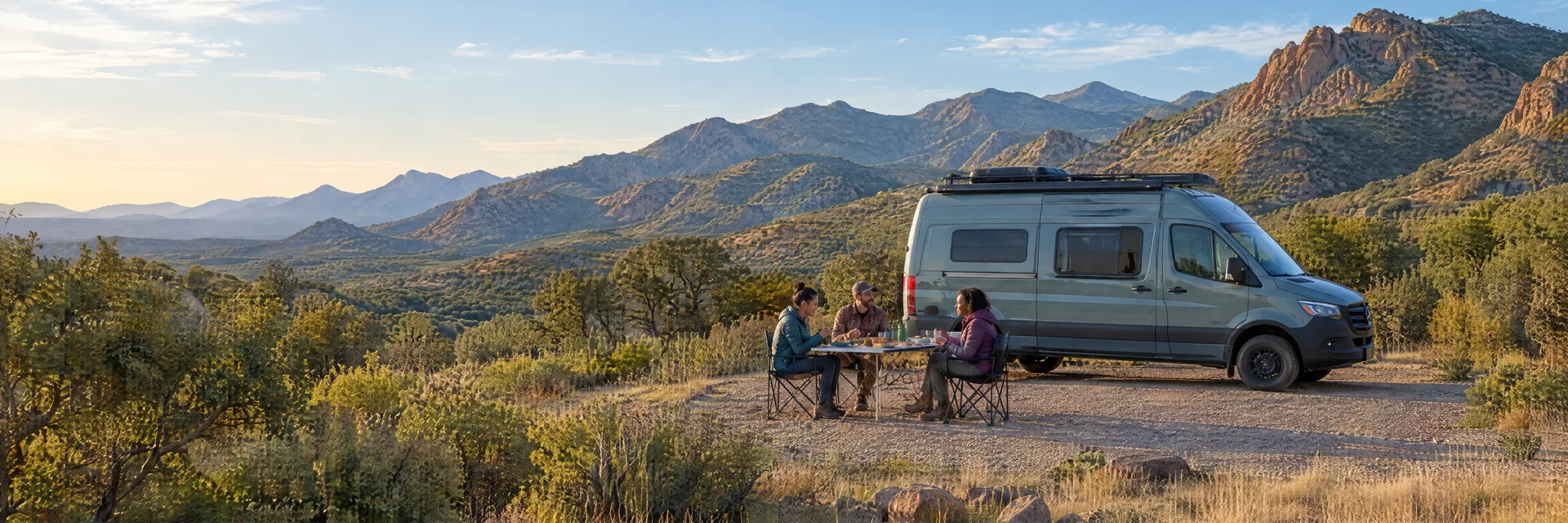 Illustration of campers enjoying an outdoor meal beside a camper van in a fictional camping setting inspired by Bisbee, AZ.