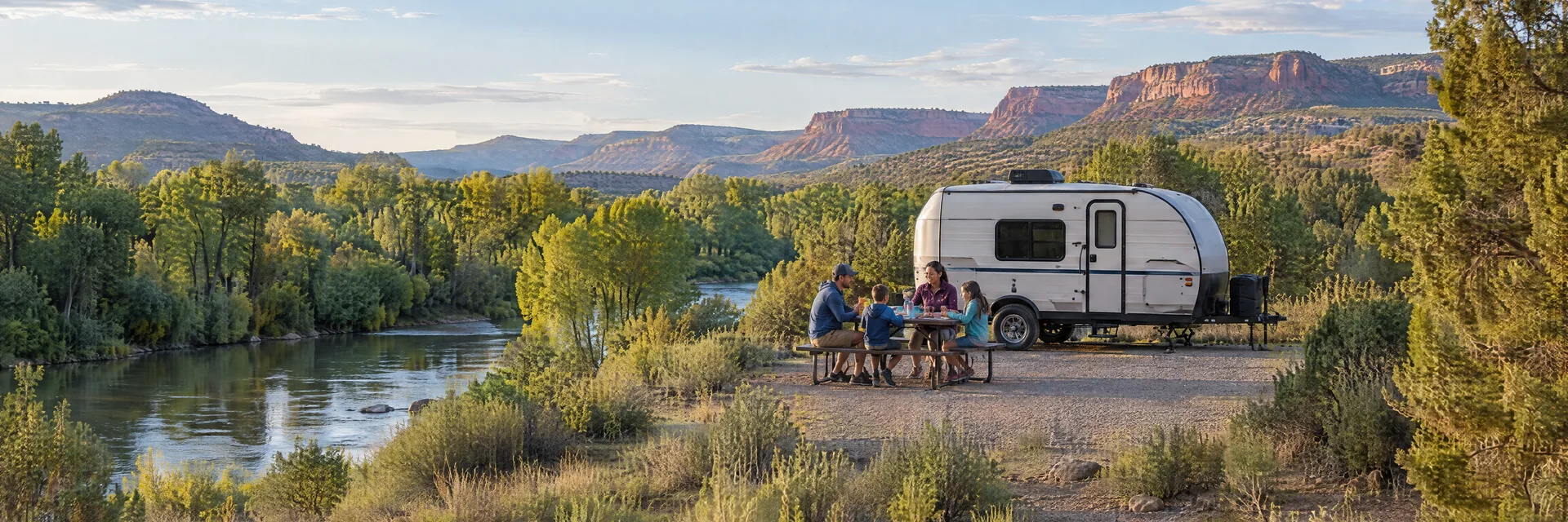Illustration of campers enjoying a family picnic beside a compact travel trailer in a fictional camping setting inspired by Cottonwood, AZ.
