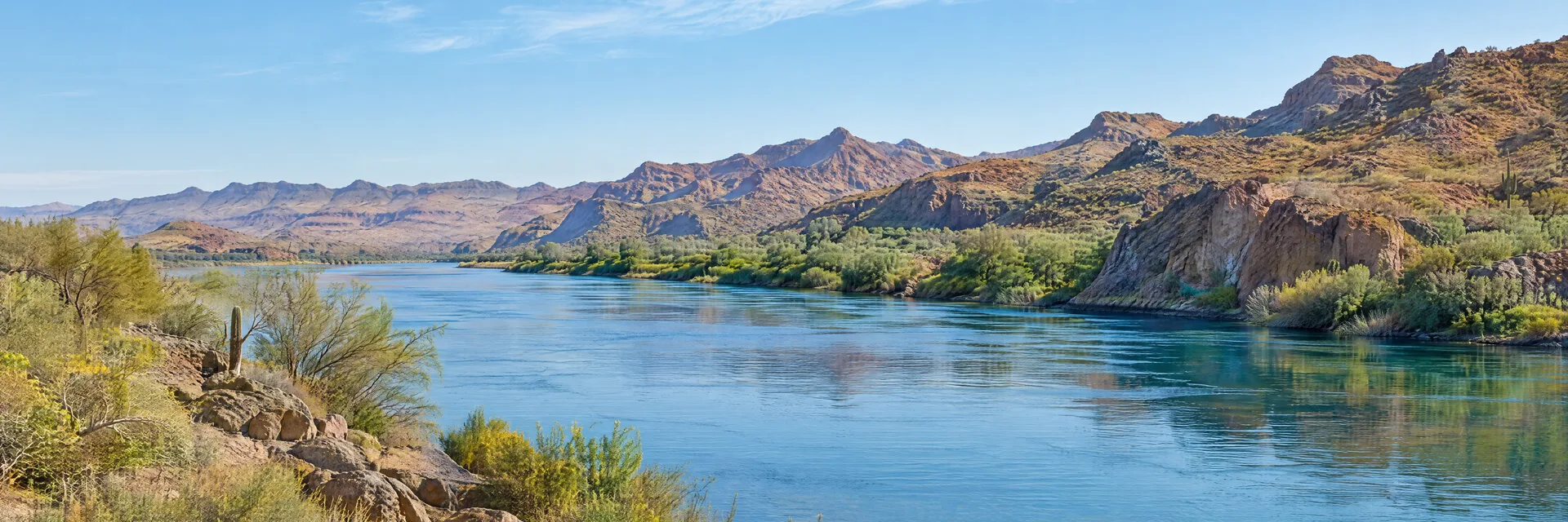 Illustration inspired by Parker, AZ: arizona Colorado River corridor, clear blue water, sparse native vegetation and dry rugged hills.
