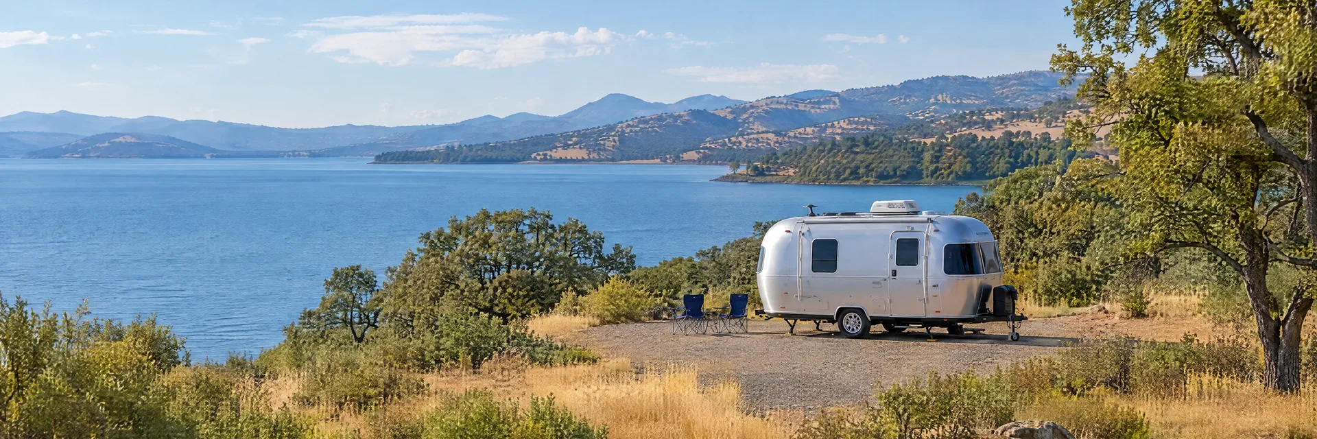 Illustration of a rounded silver travel trailer at a fictional camping setting inspired by Lakeport, CA.