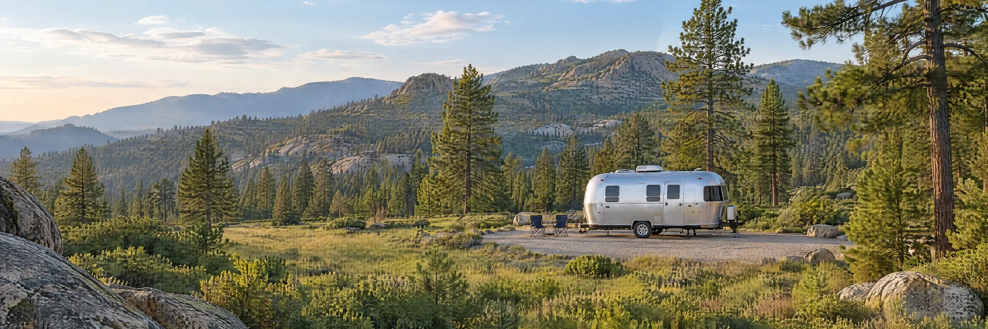 Illustration of a rounded silver travel trailer at a fictional camping setting inspired by Mt. Laguna, CA.