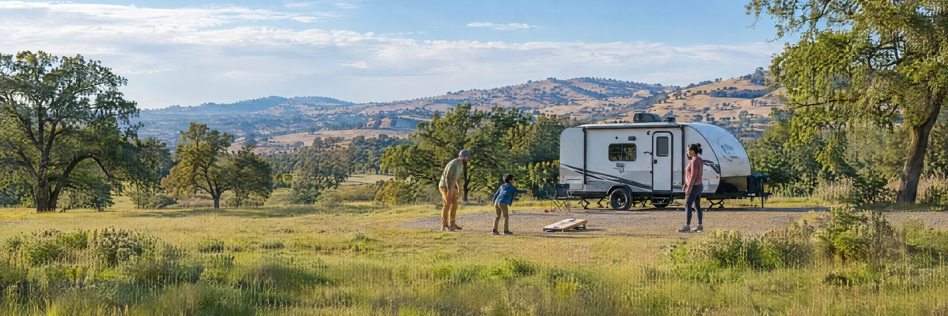 Illustration of campers enjoying family campsite activities beside a compact travel trailer in a fictional camping setting inspired by Orland, CA.