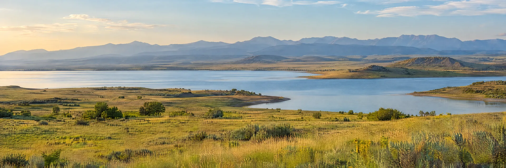 Illustration inspired by Aurora, CO: colorado eastern Front Range plains, open golden-green prairie, a calm freshwater reservoir and distant hazy mountain ridges.