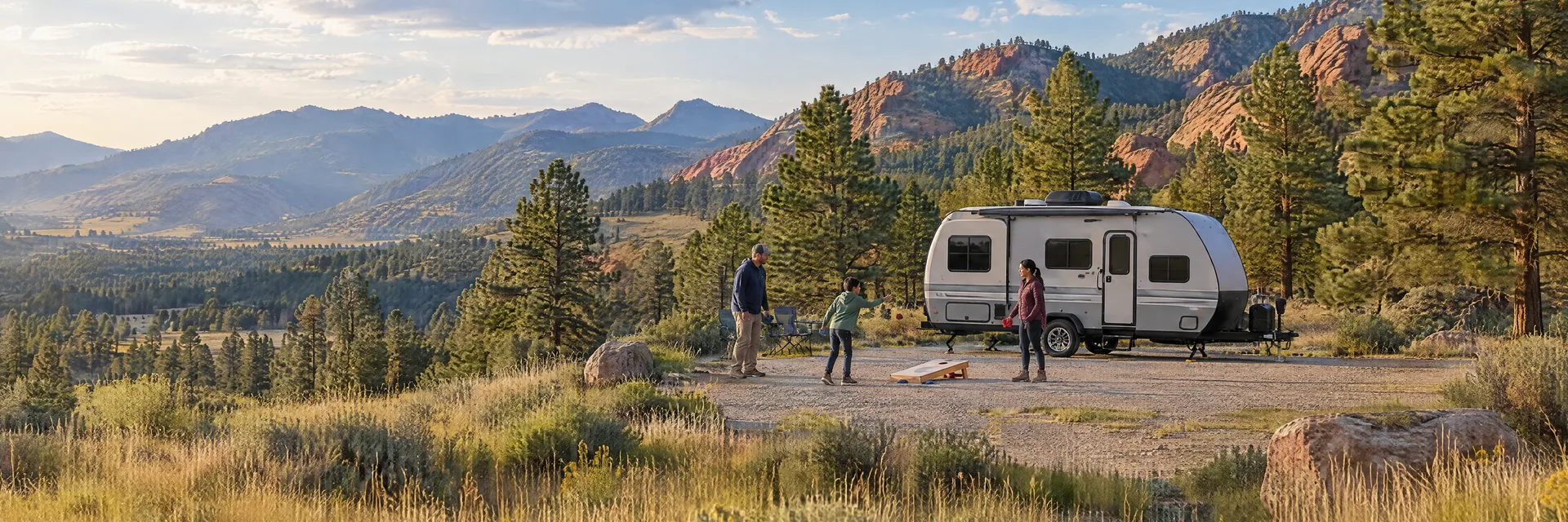 Illustration of campers enjoying family campsite activities beside a compact travel trailer in a fictional camping setting inspired by Boulder, CO.