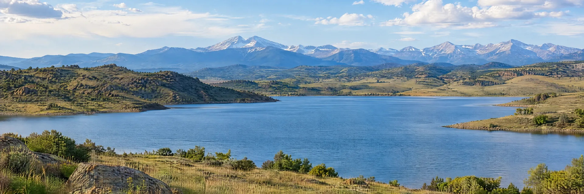 Illustration inspired by Loveland, CO: colorado foothill reservoir with grasslands and distant Rocky Mountain ridges.