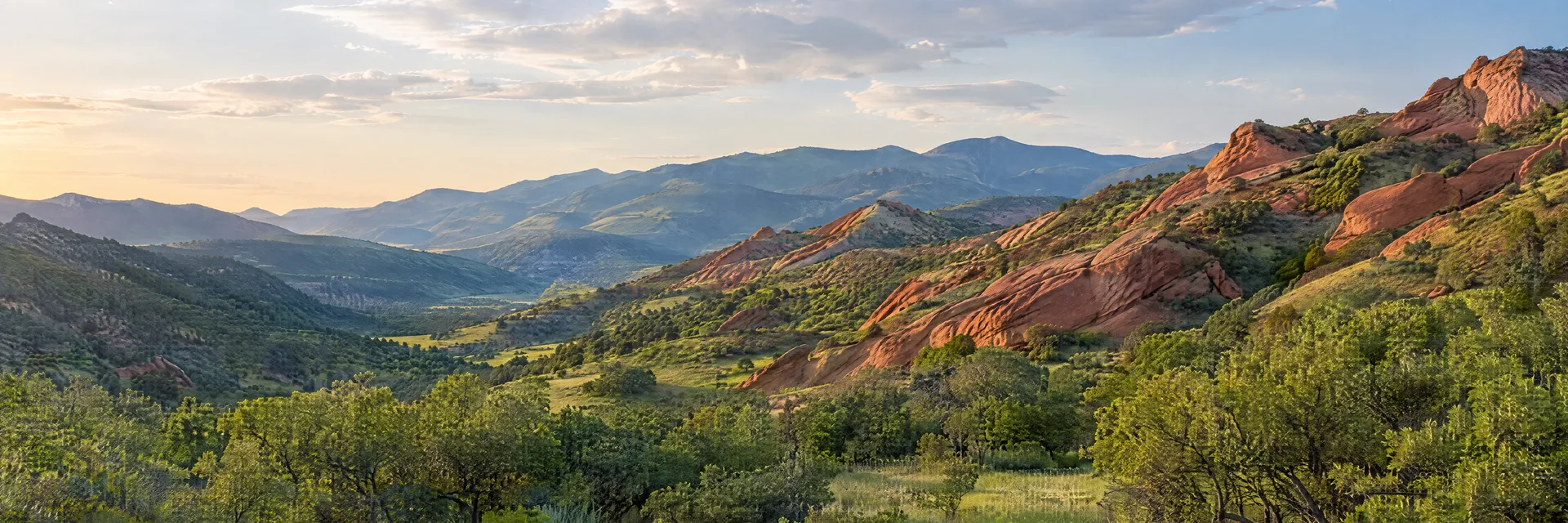 Illustration inspired by Morrison, CO: colorado Front Range foothills with red sandstone slopes, scrub oak and green meadow; no amphitheater.