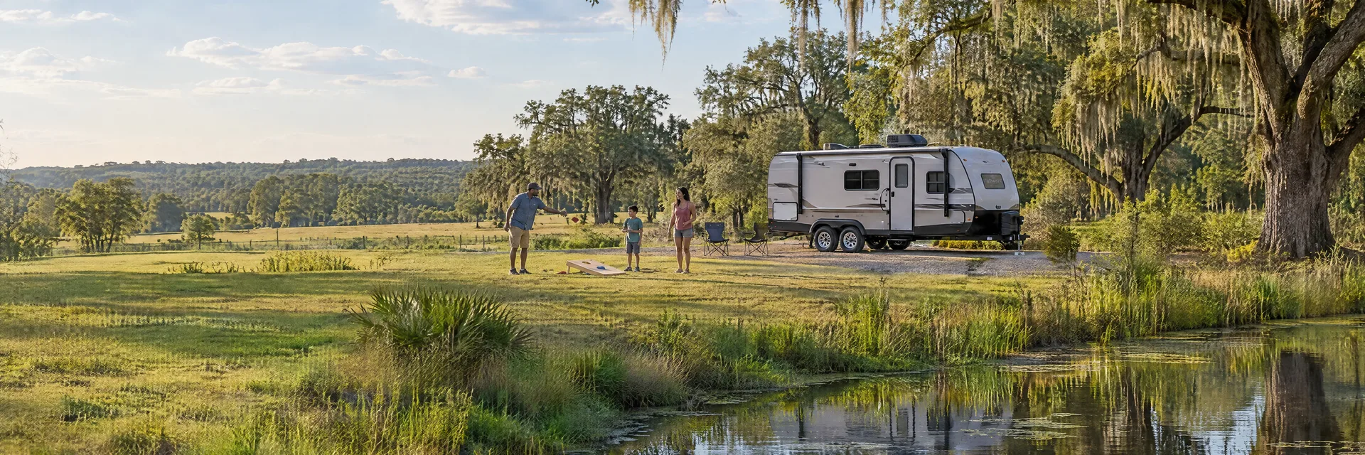 Illustration of campers enjoying family campsite activities beside a compact travel trailer in a fictional camping setting inspired by Brooksville, FL.
