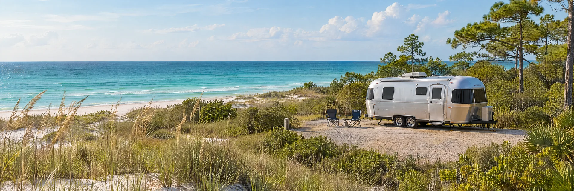 Illustration of a rounded silver travel trailer at a fictional camping setting inspired by Fort Walton Beach, FL.