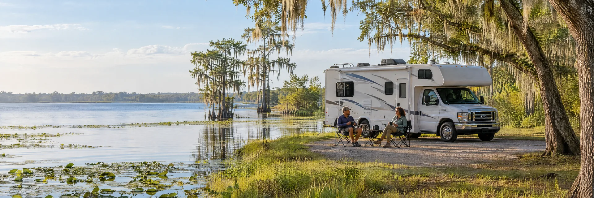 Illustration of campers enjoying morning coffee beside a Class C motorhome in a fictional camping setting inspired by Lake Panasoffkee, FL.