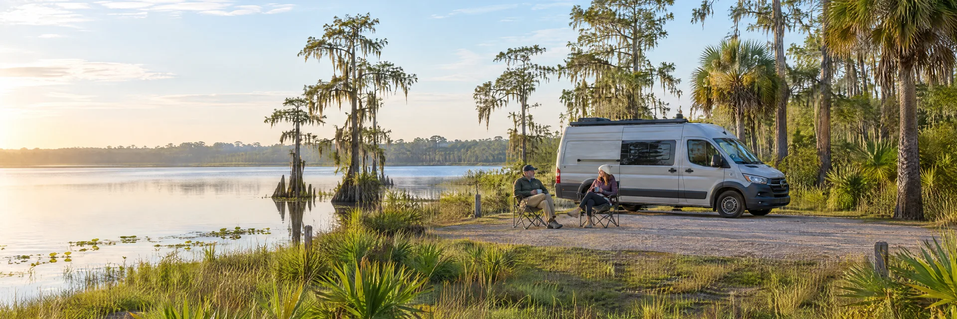 Illustration of campers enjoying morning coffee beside a camper van in a fictional camping setting inspired by Lake Placid, FL.