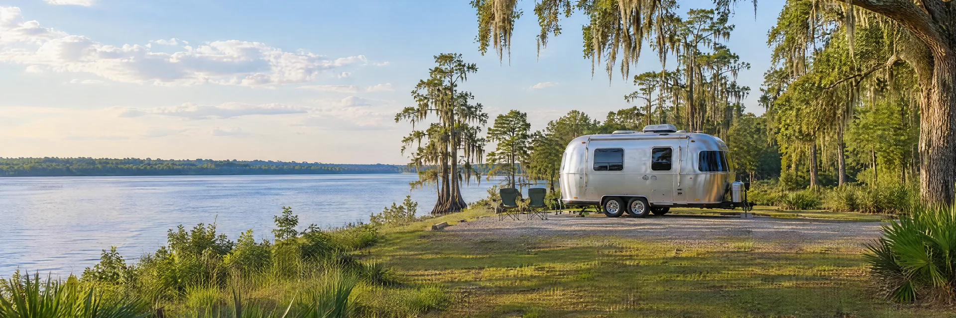 Illustration of a rounded silver travel trailer at a fictional camping setting inspired by Palatka, FL.