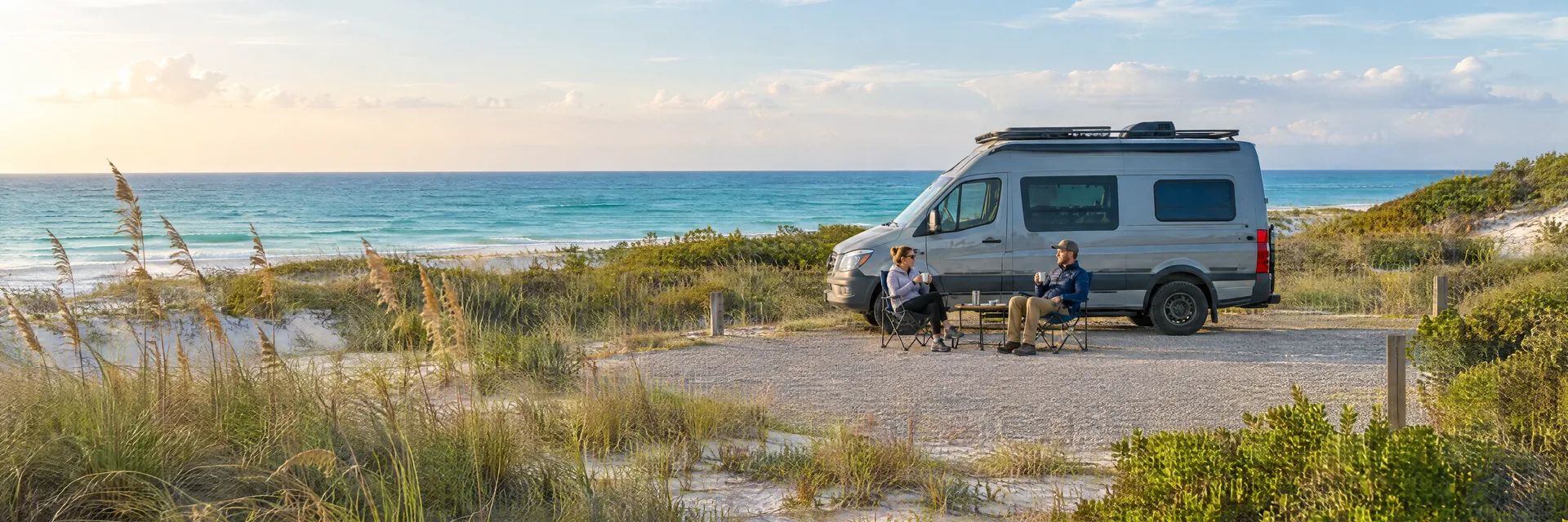 Illustration of campers enjoying morning coffee beside a camper van in a fictional camping setting inspired by Pensacola Beach, FL.