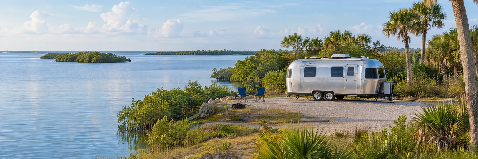 Illustration of a rounded silver travel trailer at a fictional camping setting inspired by Roseland, FL.