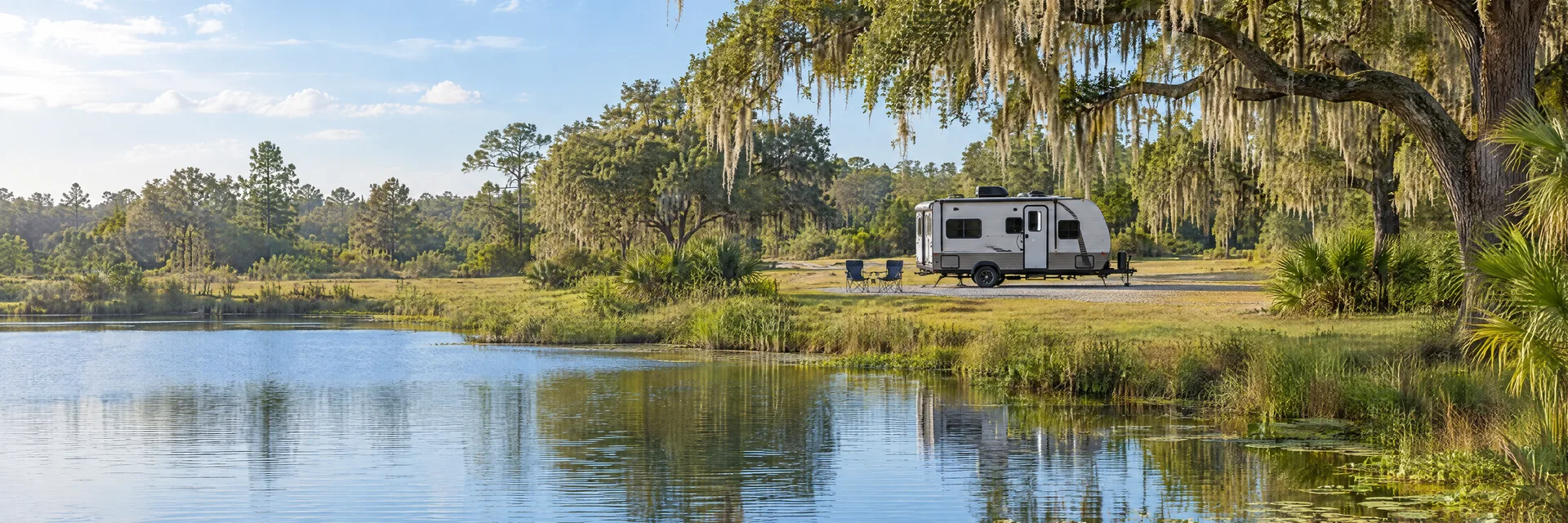 Illustration of a compact travel trailer at a fictional camping setting inspired by Summerfield, FL.
