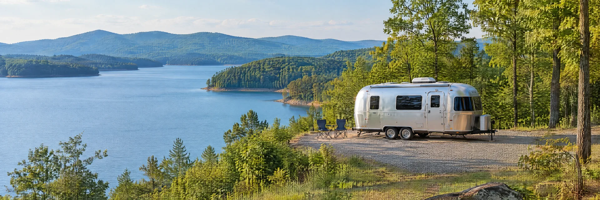 Illustration of a rounded silver travel trailer at a fictional camping setting inspired by Gainesville, GA.