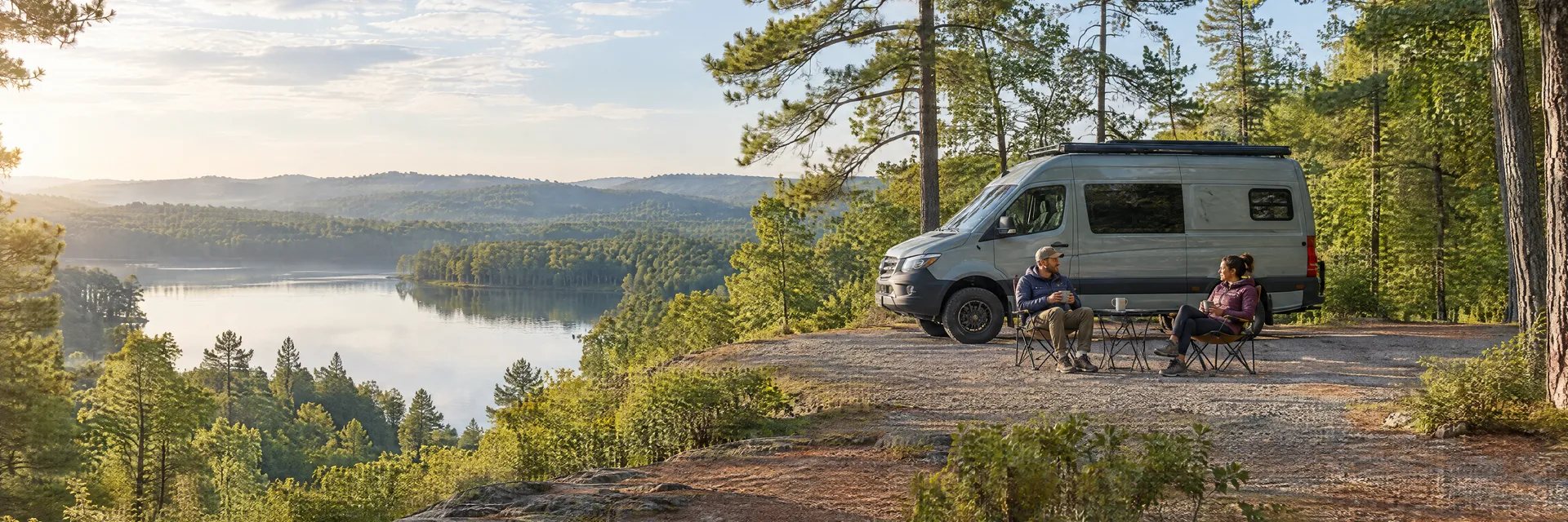 Illustration of campers enjoying morning coffee beside a camper van in a fictional camping setting inspired by PINE MOUNTAIN, GA.