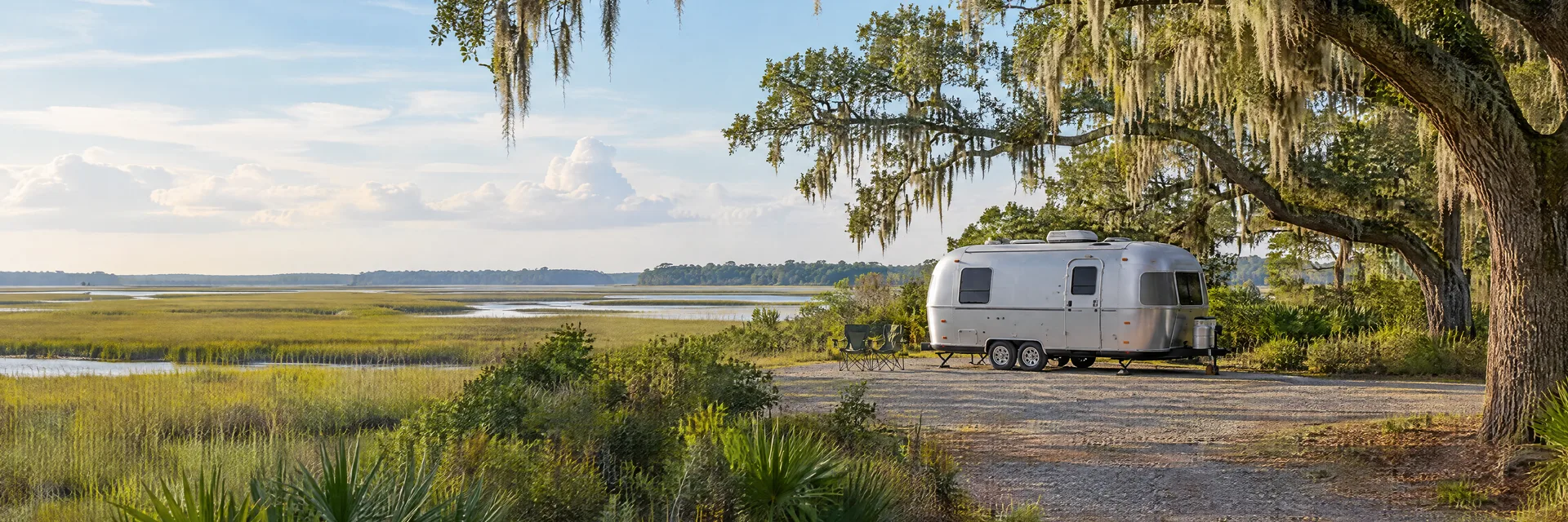 Illustration of a rounded silver travel trailer at a fictional camping setting inspired by Savannah, GA.