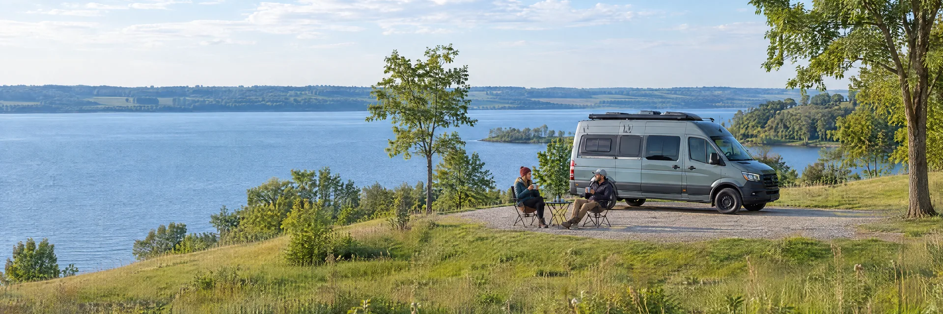 Illustration of campers enjoying morning coffee beside a camper van in a fictional camping setting inspired by Spirit Lake, IA.