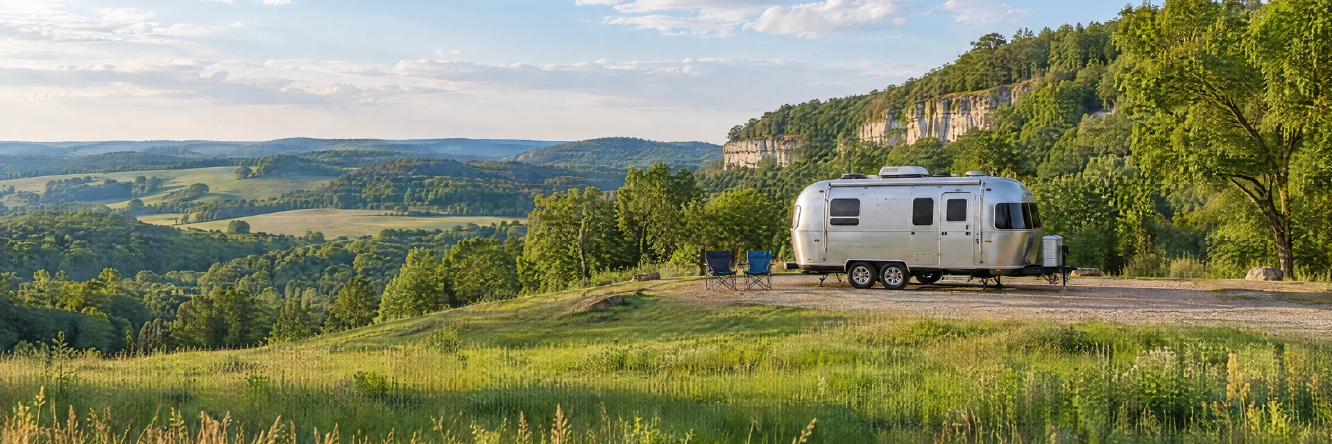 Illustration of a rounded silver travel trailer at a fictional camping setting inspired by Galena, IL.