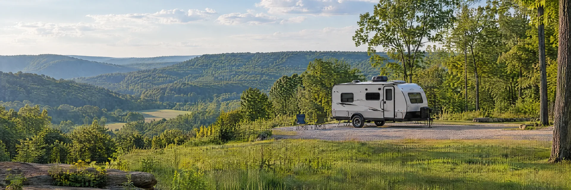 Illustration of a compact travel trailer at a fictional camping setting inspired by French Lick, IN.