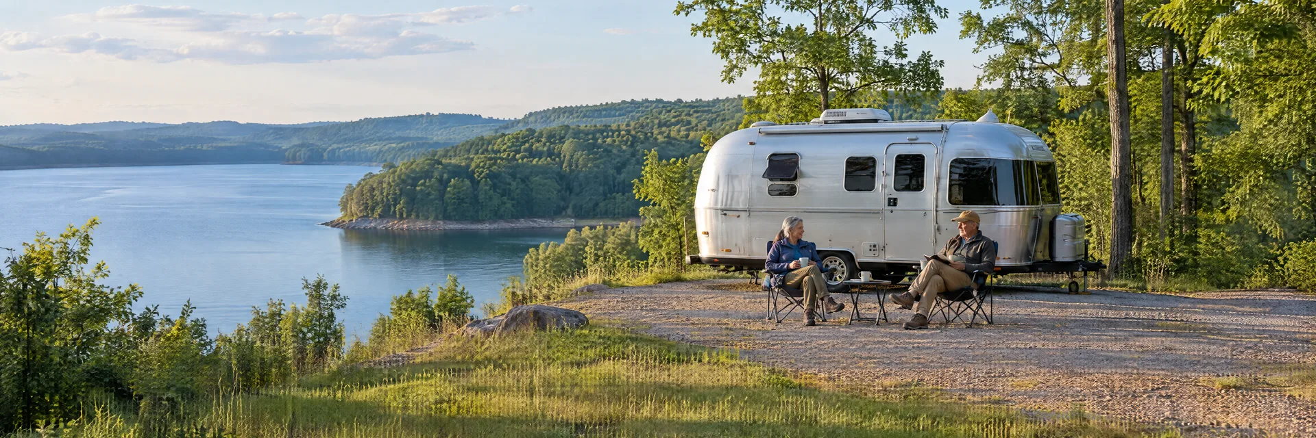 Illustration of campers enjoying relaxing at camp beside a rounded silver travel trailer in a fictional camping setting inspired by Eddyville, KY.