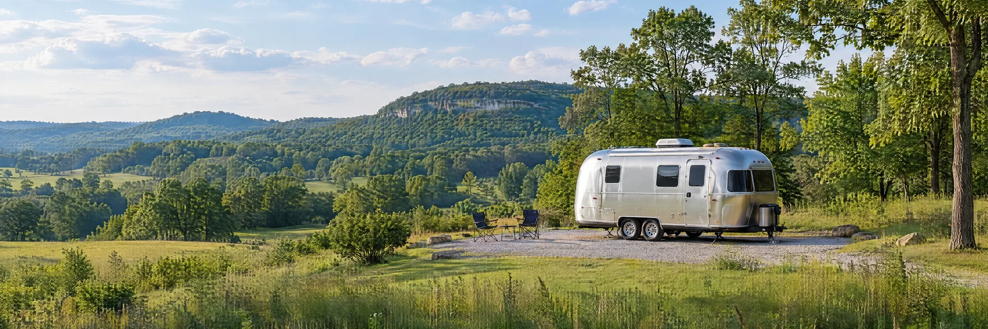 Illustration of a rounded silver travel trailer at a fictional camping setting inspired by Richmond, KY.