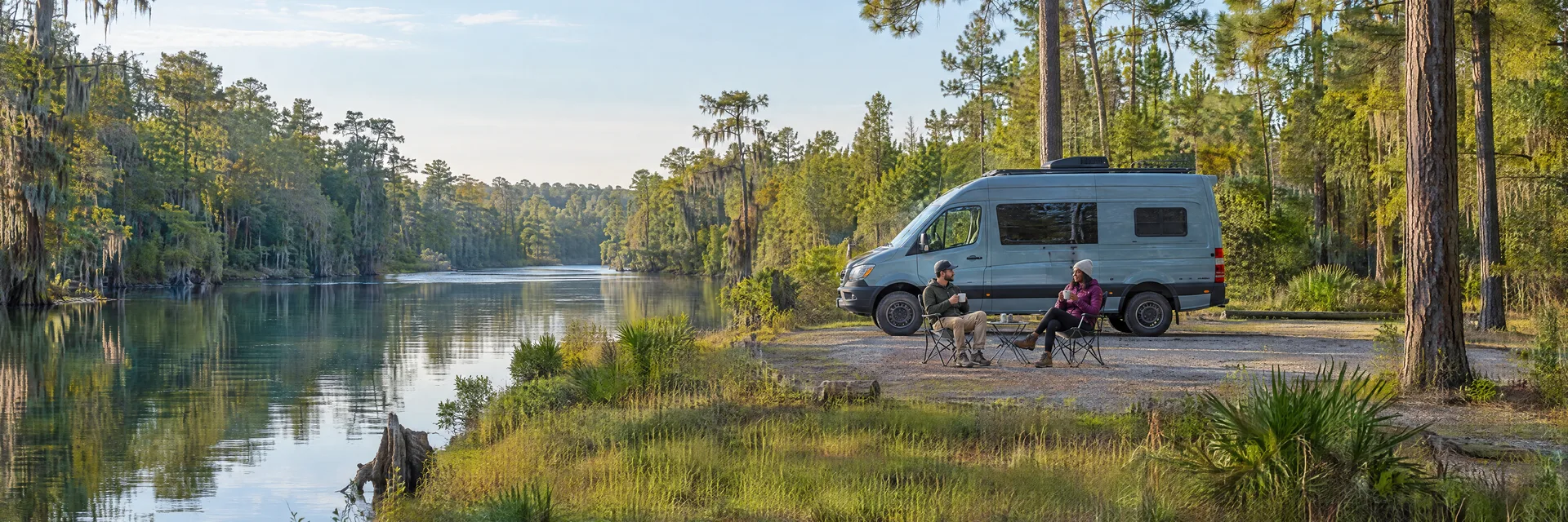 Illustration of campers enjoying morning coffee beside a camper van in a fictional camping setting inspired by Covington, LA.