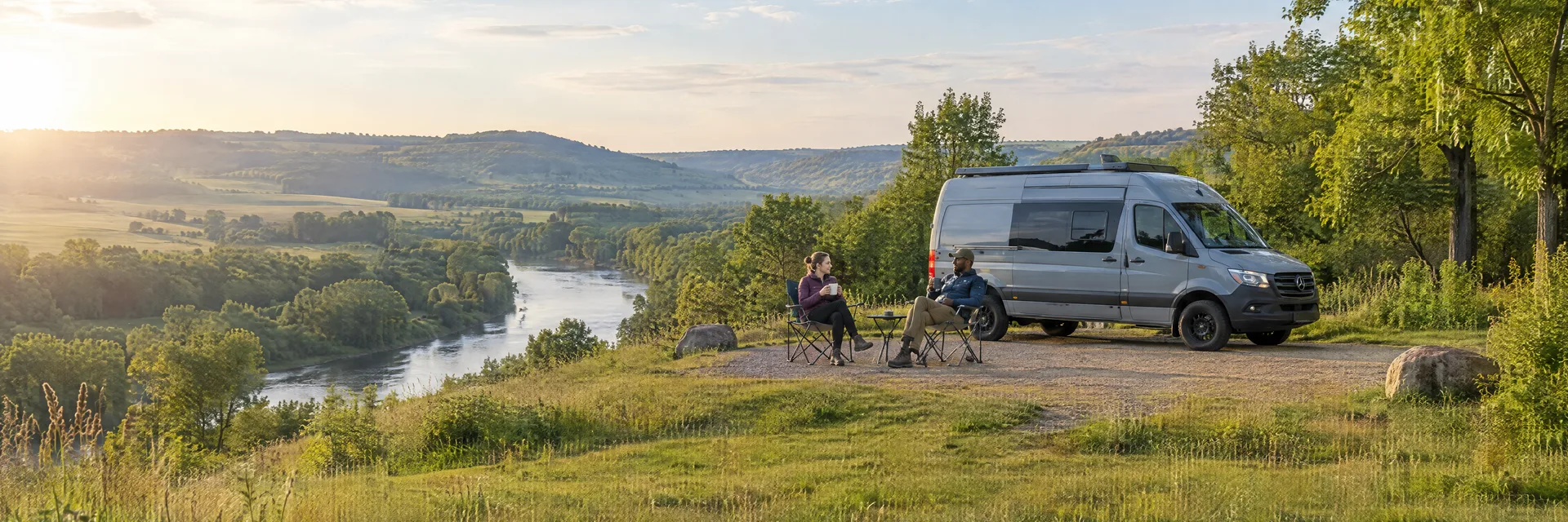 Illustration of campers enjoying morning coffee beside a camper van in a fictional camping setting inspired by Ionia, MI.