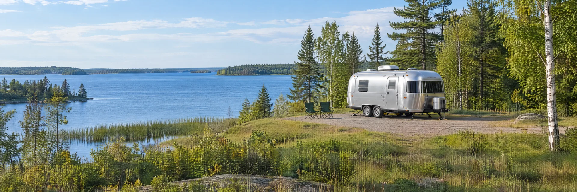 Illustration of a rounded silver travel trailer at a fictional camping setting inspired by Federal Dam, MN.