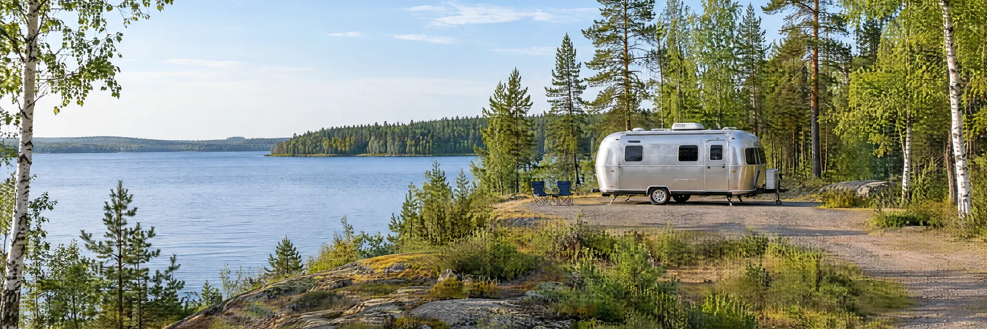Illustration of a rounded silver travel trailer at a fictional camping setting inspired by McGregor, MN.