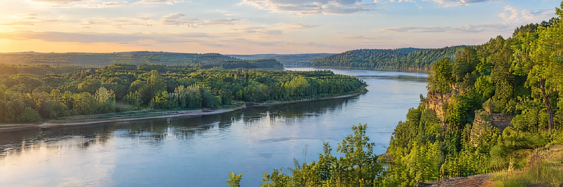 Illustration inspired by Stillwater, MN: st Croix Valley broad river bend with leafy wooded bluffs and soft summer light.