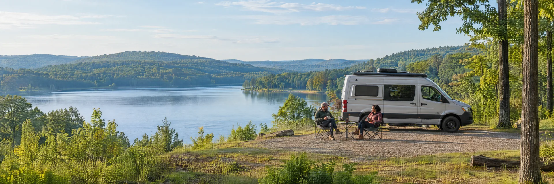 Illustration of campers enjoying morning coffee beside a camper van in a fictional camping setting inspired by Oxford, MS.