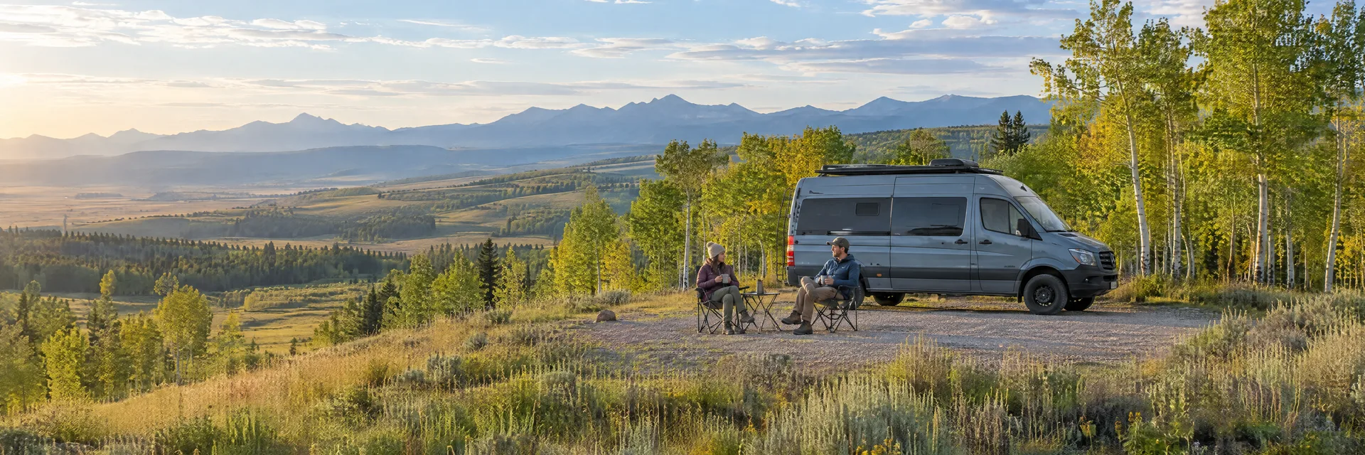 Illustration of campers enjoying morning coffee beside a camper van in a fictional camping setting inspired by St. Mary, MT.