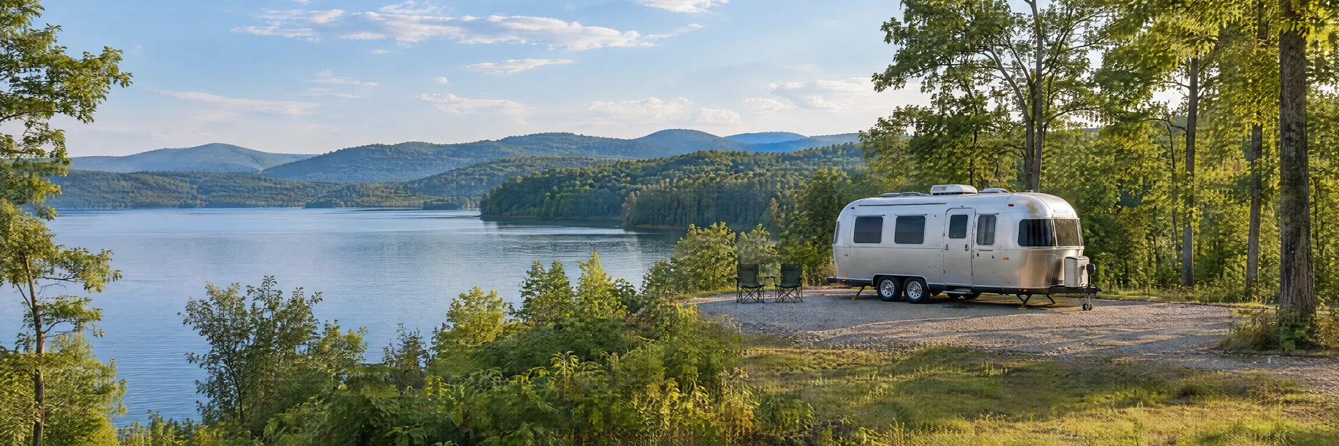 Illustration of a rounded silver travel trailer at a fictional camping setting inspired by Charlotte, NC.