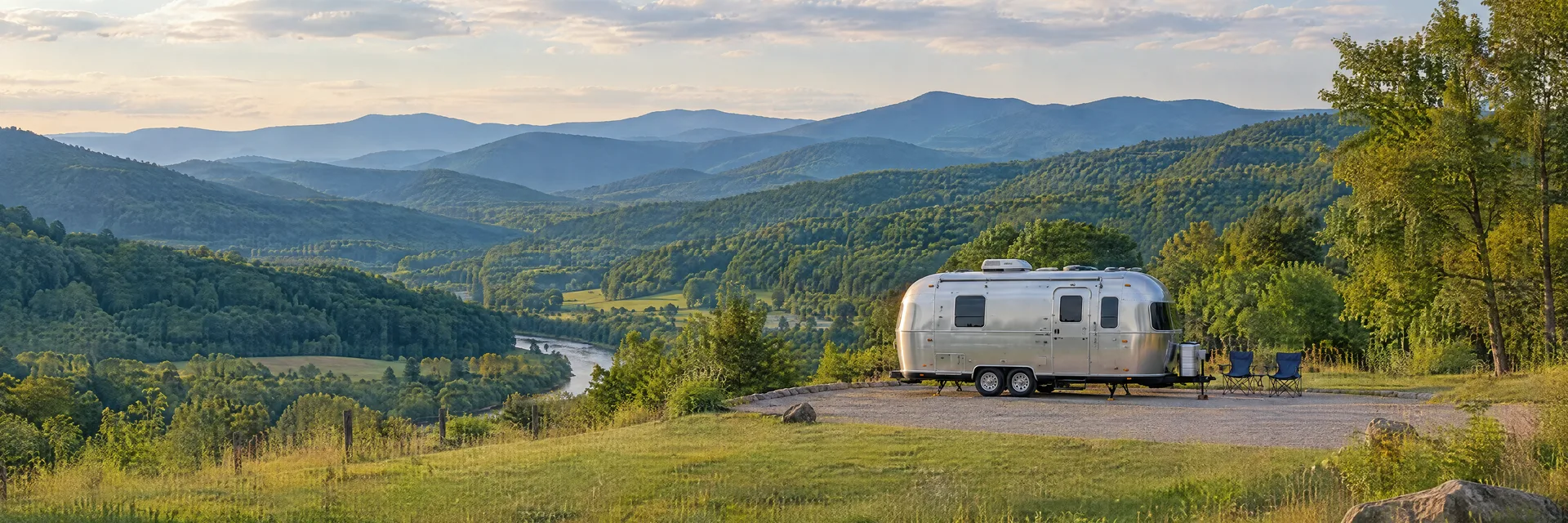 Illustration of a rounded silver travel trailer at a fictional camping setting inspired by Fleetwood, NC.