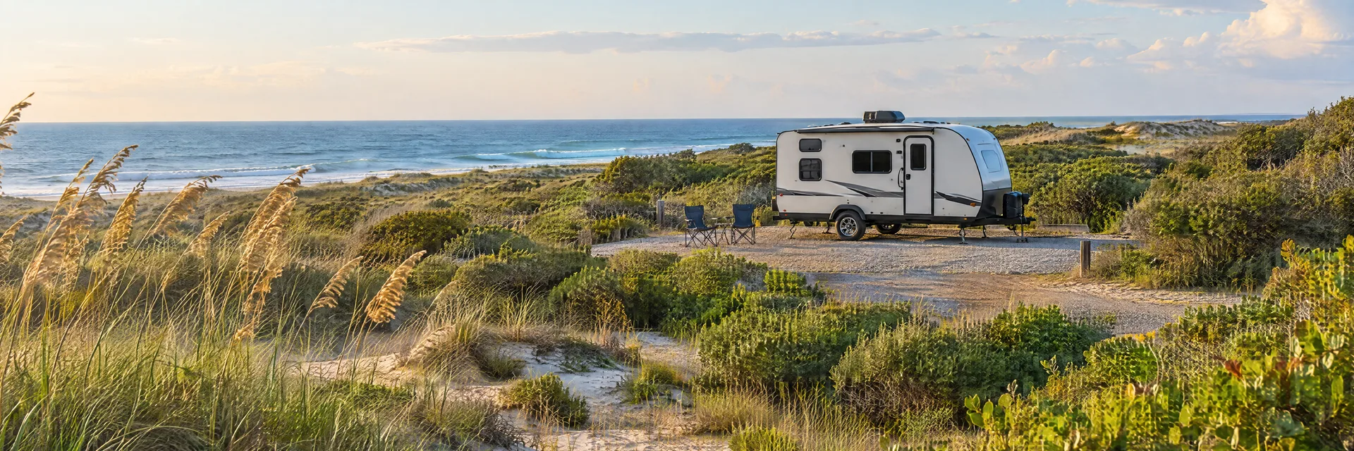 Illustration of a compact travel trailer at a fictional camping setting inspired by Frisco, NC.