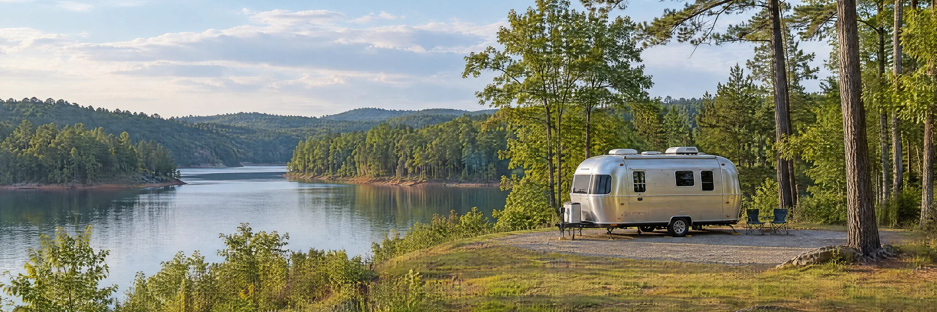 Illustration of a rounded silver travel trailer at a fictional camping setting inspired by Lexington, NC.