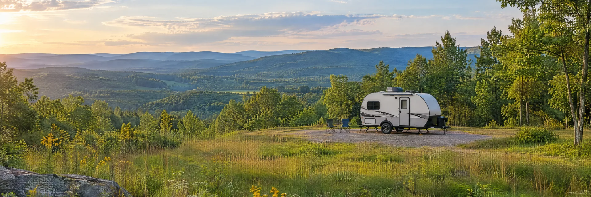 Illustration of a compact travel trailer at a fictional camping setting inspired by Pilot Mountain, NC.