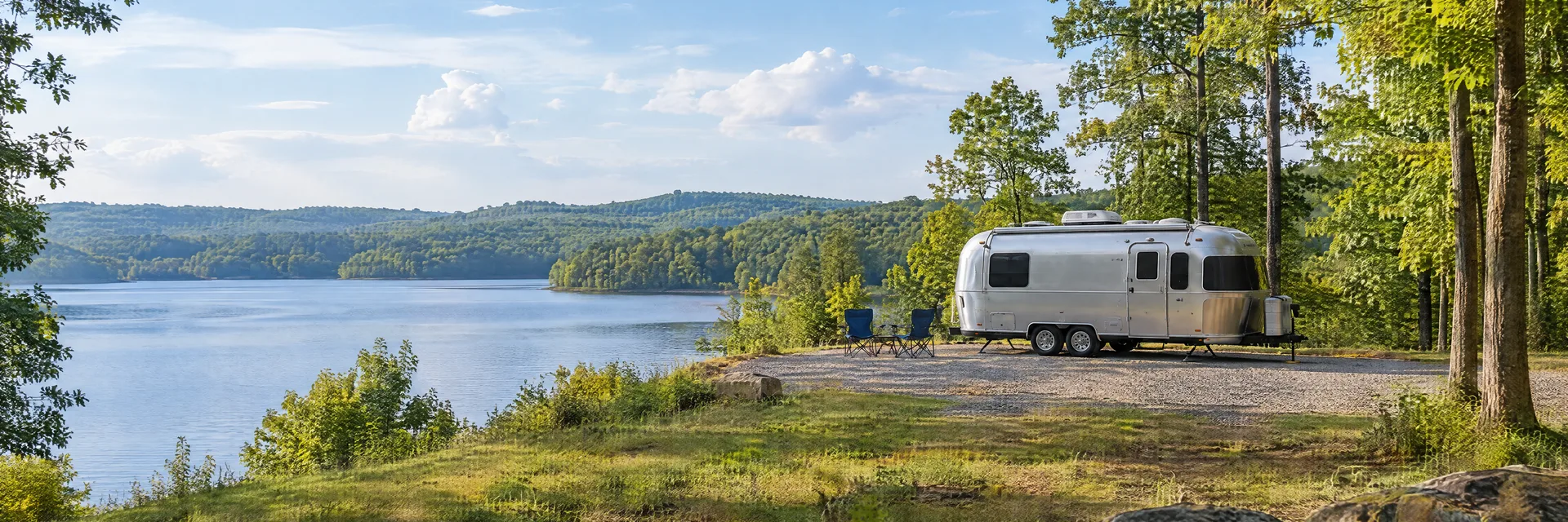 Illustration of a rounded silver travel trailer at a fictional camping setting inspired by Raleigh, NC.