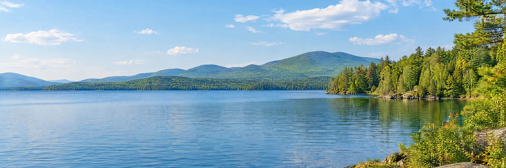 Illustration inspired by Meredith, NH: central New Hampshire lake country, clear blue water, pine and hardwood shoreline and softly rounded green mountains.