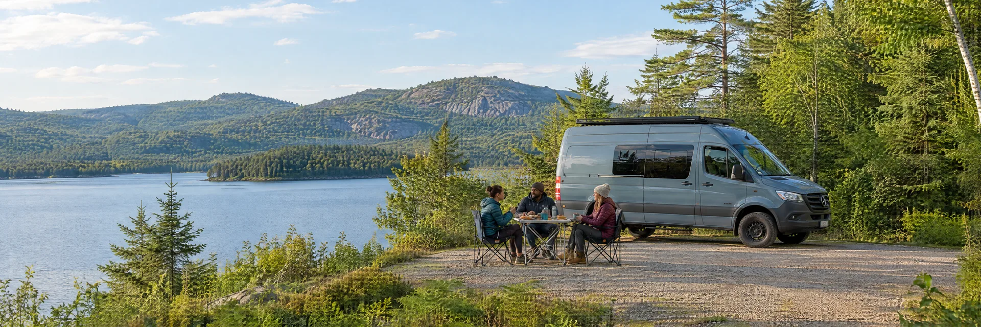 Illustration of campers enjoying an outdoor meal beside a camper van in a fictional camping setting inspired by Nelson, NH.