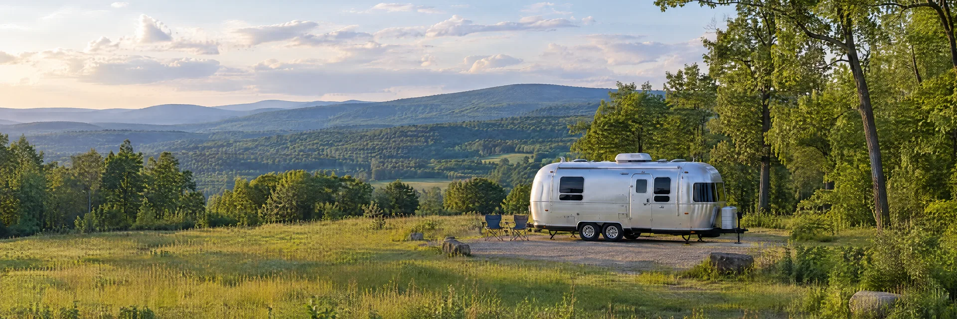 Illustration of a rounded silver travel trailer at a fictional camping setting inspired by Stone Ridge, NY.