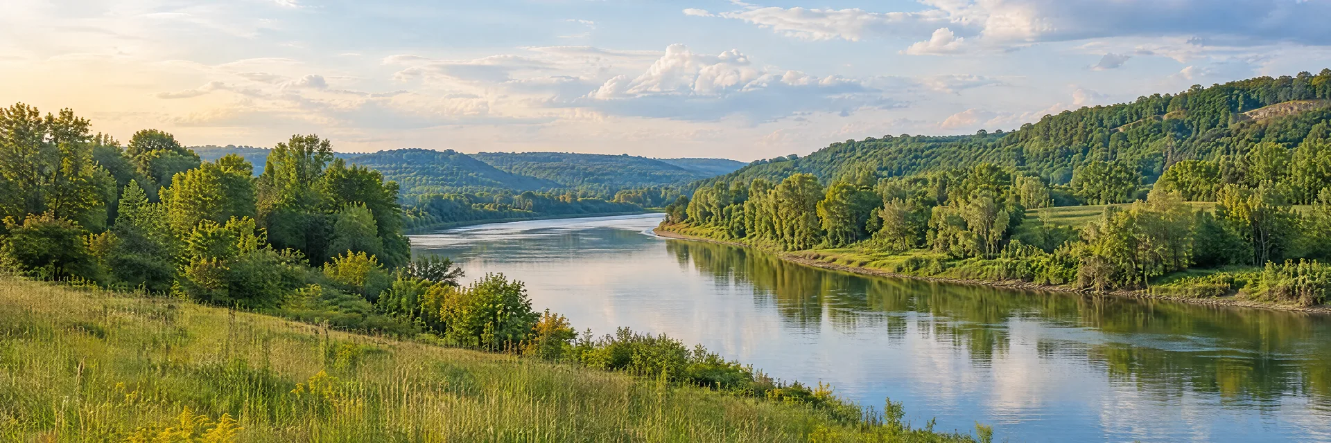 Illustration inspired by Dayton, OH: southwestern Ohio leafy river bend with green meadow and low wooded hills.