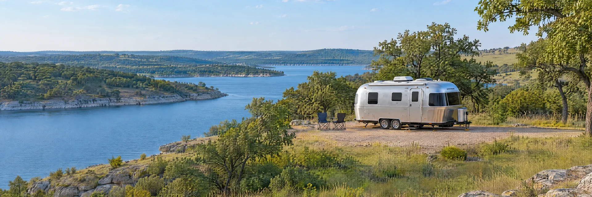Illustration of a rounded silver travel trailer at a fictional camping setting inspired by Ardmore, OK.