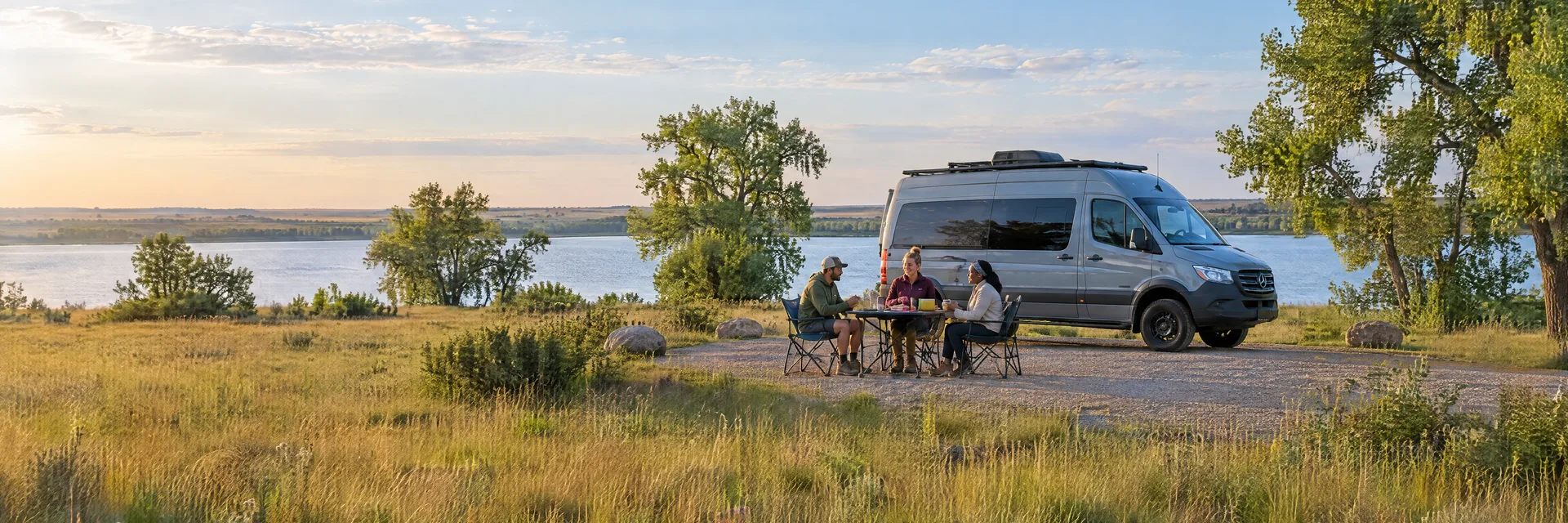 Illustration of campers enjoying an outdoor meal beside a camper van in a fictional camping setting inspired by El Reno, OK.