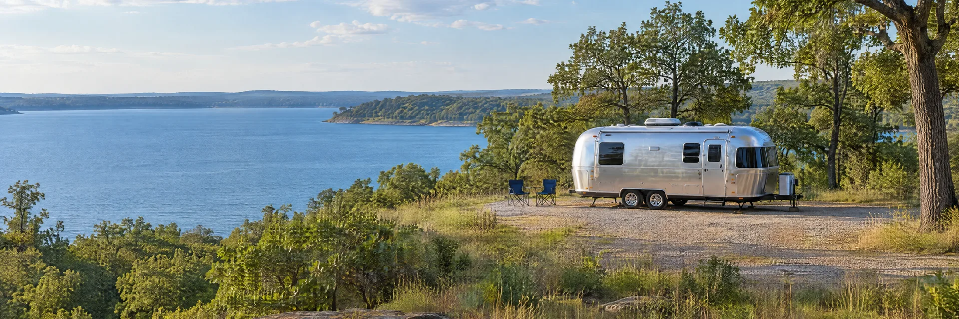 Illustration of a rounded silver travel trailer at a fictional camping setting inspired by Eufaula, OK.