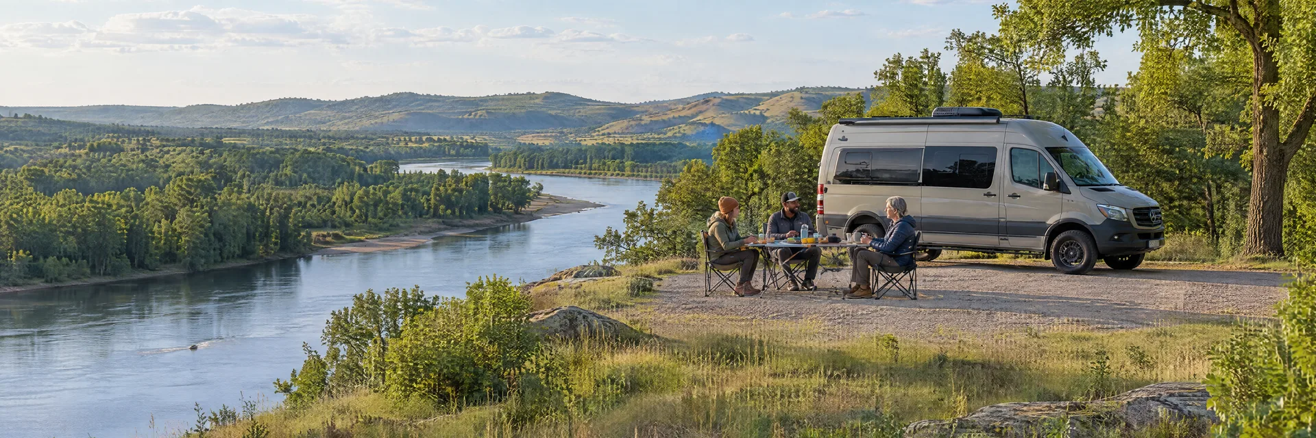 Illustration of campers enjoying an outdoor meal beside a camper van in a fictional camping setting inspired by Sand Hill, OK.
