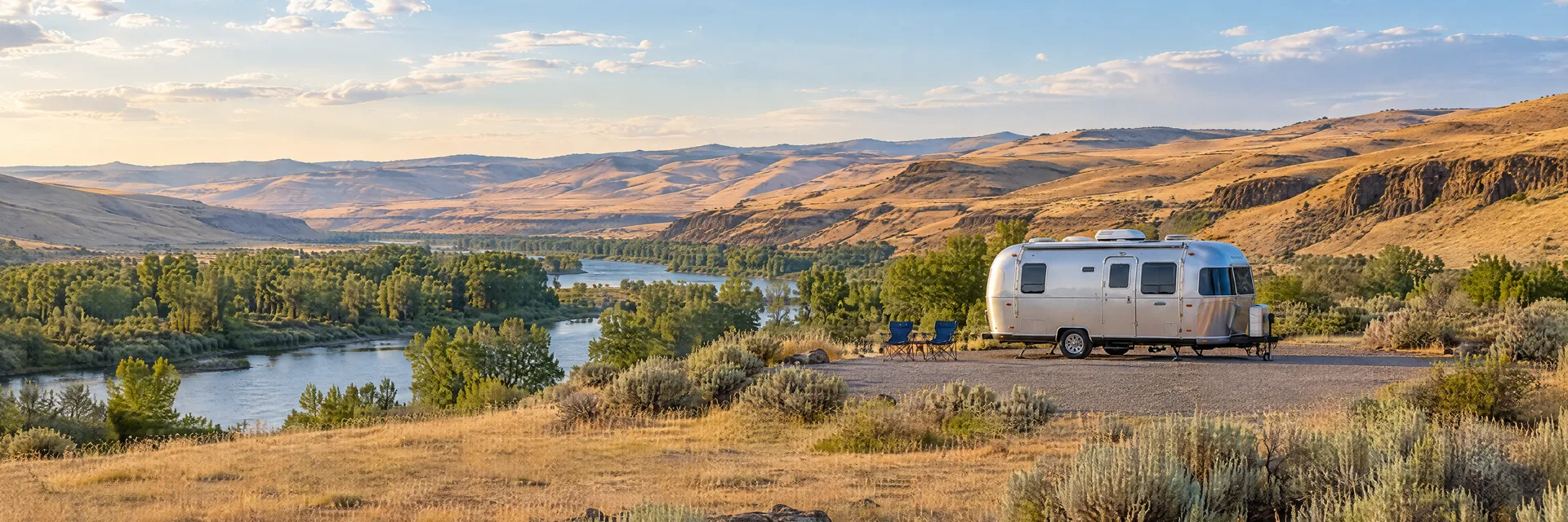 Illustration of a rounded silver travel trailer at a fictional camping setting inspired by Echo, OR.